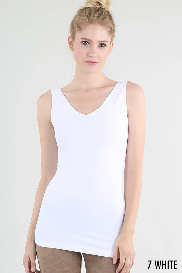Woman wearing a white tank top against a plain background
