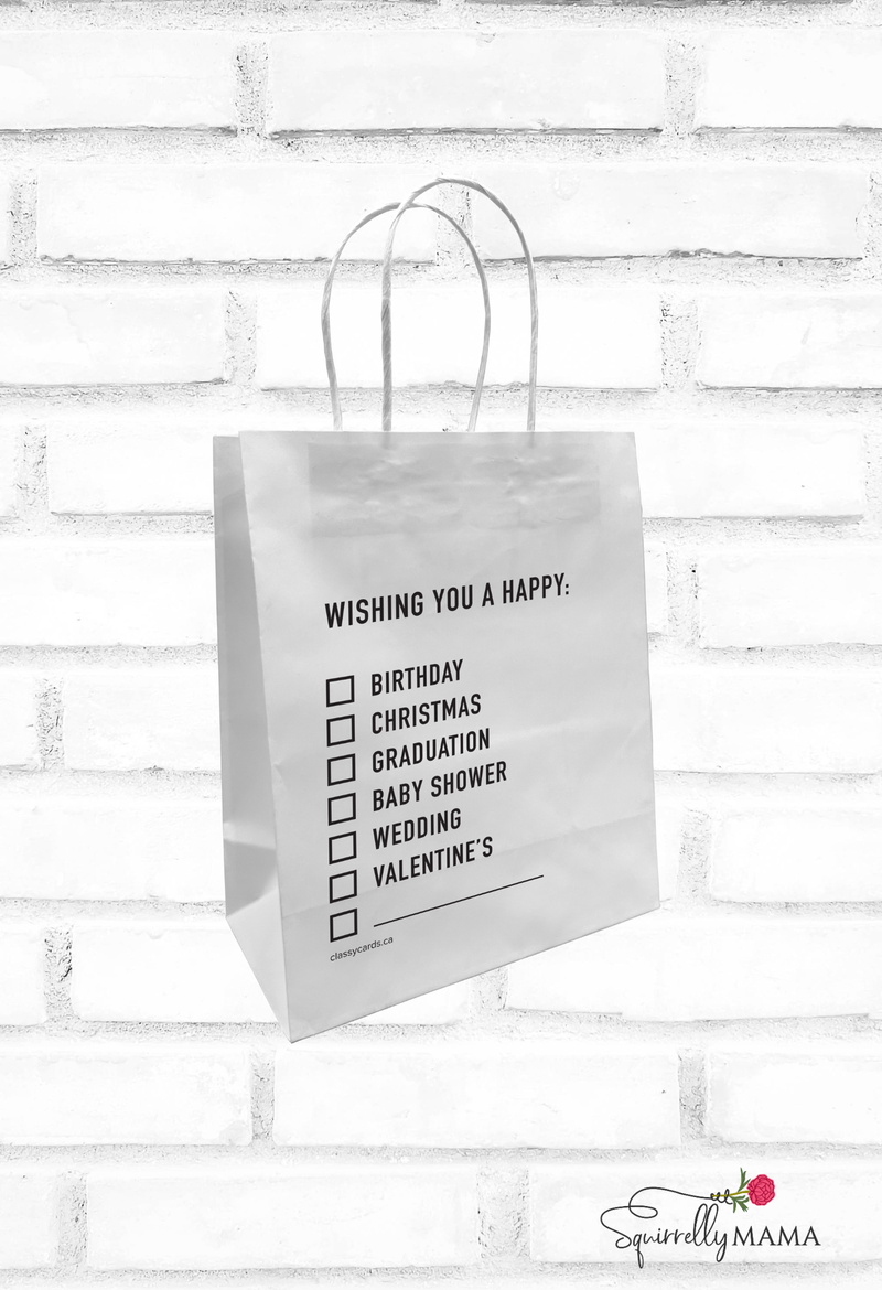 White gift bag with black text and checkboxes on a white brick wall background