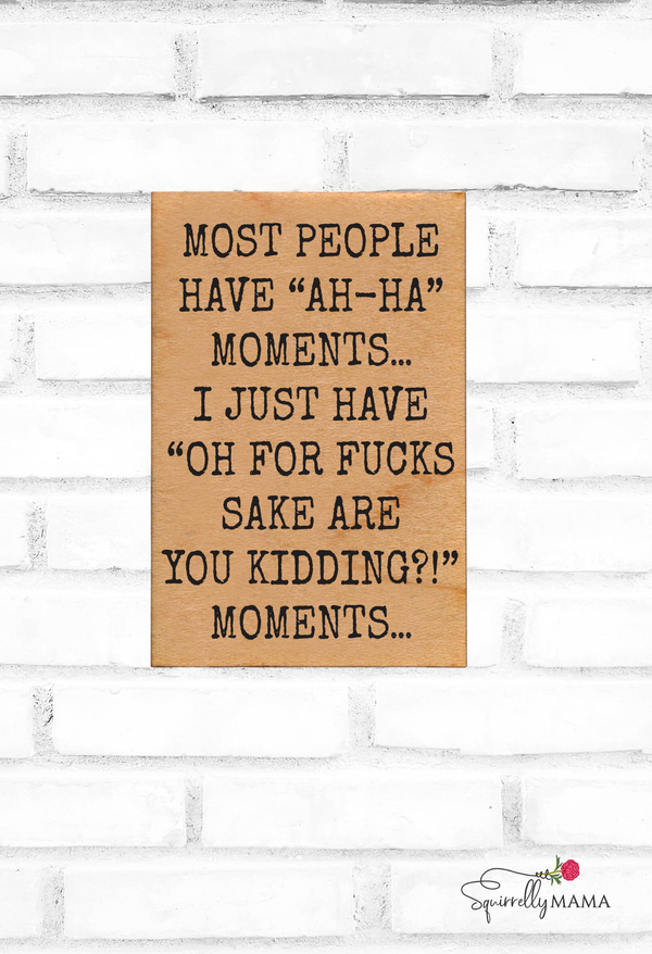 Wooden magnet with humorous and adult text on a white brick wall