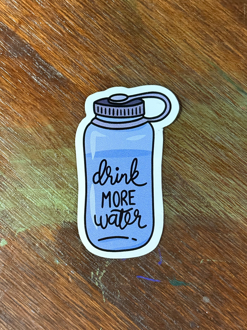 Sticker of a water bottle with 'drink more water' text on a wooden surface