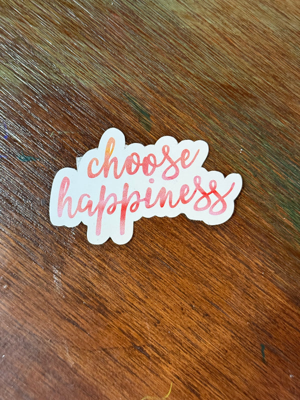 Sticker with 'choose happiness' text on a wooden surface