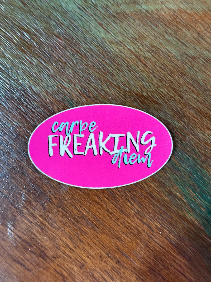 Pink oval sticker with white text on a wooden surface