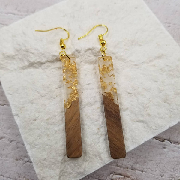 Wooden and gold earrings on a textured surface