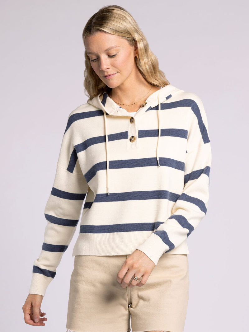 Woman wearing a cream and navy striped hooded sweater with button front and drawstrings.”
