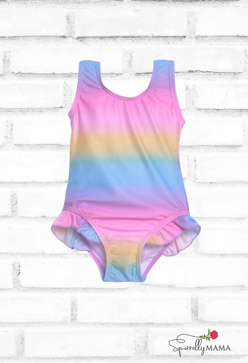 Multicolored tie-dye toddler swimsuit on a white brick background