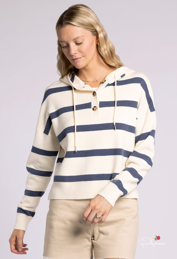 Woman wearing a cream and navy striped hooded sweater with button front and drawstrings.”
