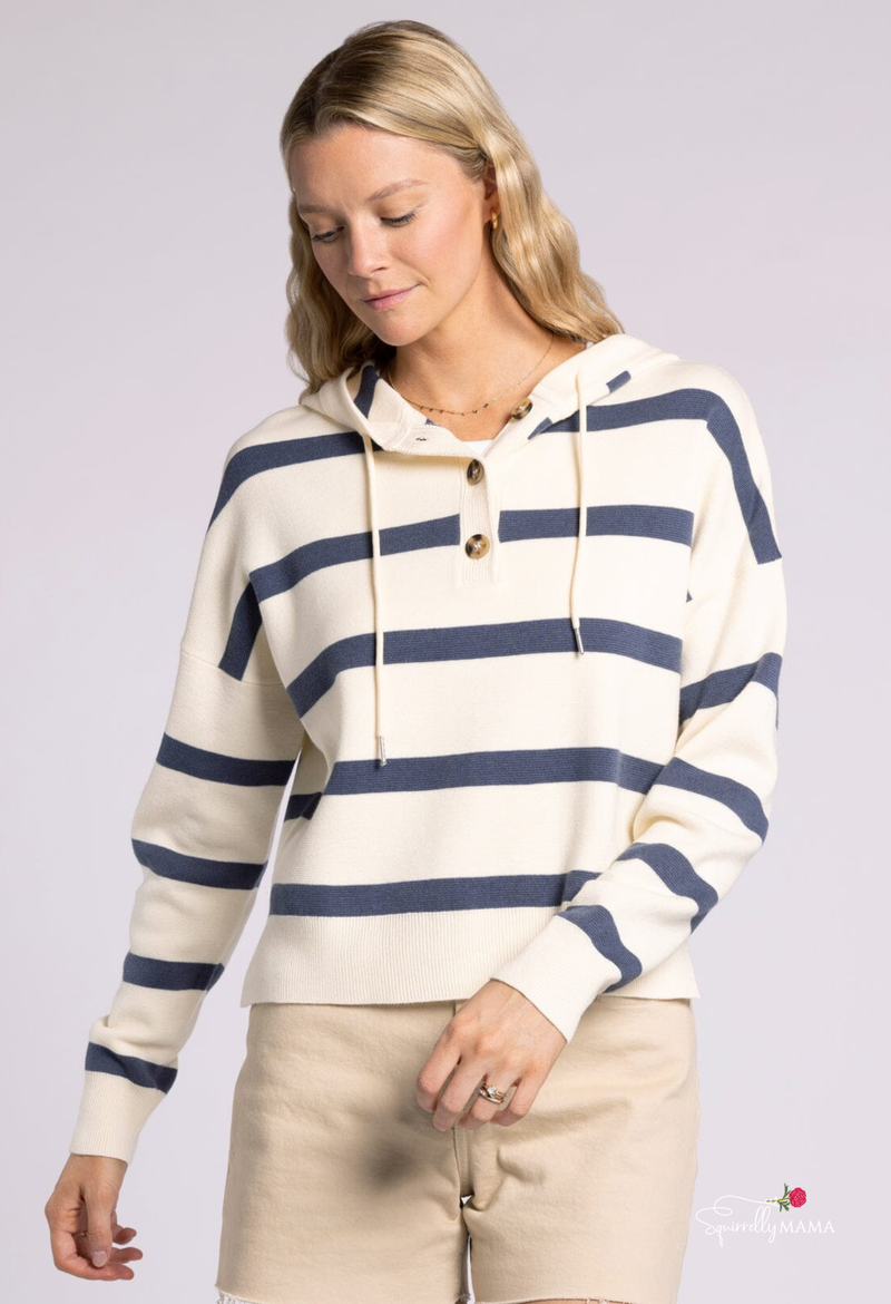 Woman wearing a cream and navy striped hooded sweater with button front and drawstrings.”
