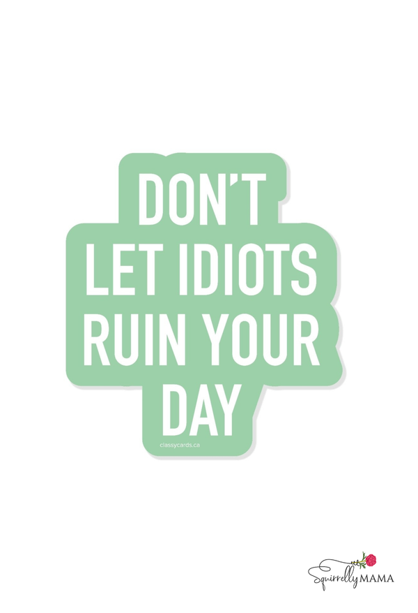 Funny motivational quote 'Don't let idiots ruin your day' on a light green background with a brand logo at the bottom right corner.