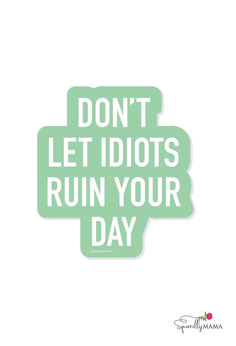 Funny motivational quote 'Don't let idiots ruin your day' on a light green background with a brand logo at the bottom right corner.